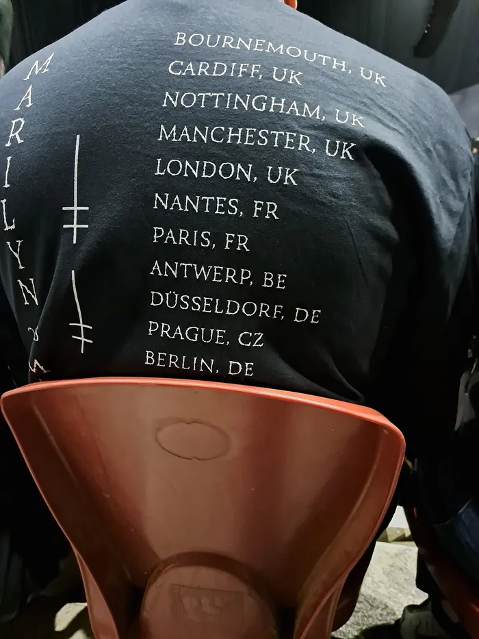 The back of a black tour shirt listing the tour's cities